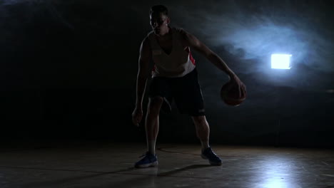 one-young-adult-man,-basketball-player-dribble-ball,-dark-indoors-basketball-court-slow-motion